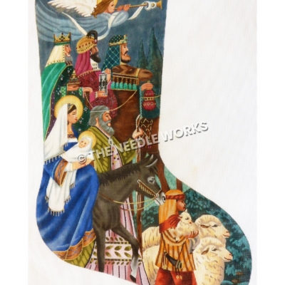 blue stocking with nativity theme showing angel flying with trumpet, three wise men with gifts, Mary on donkey holding baby Jesus, Joseph walking next to Mary and boy shepherd with sheep