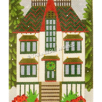 white two story house with red and green roof and wreath on door with tall evergreen trees on either side
