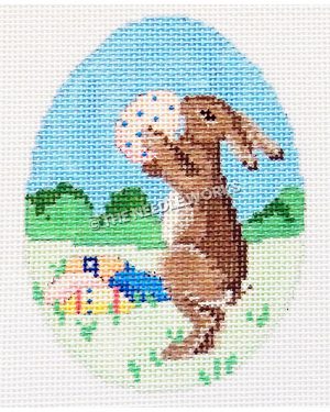 Easter egg with brown bunny holding white egg with blue dots with eggs sitting in prairie landscape with green bushes and blue sky