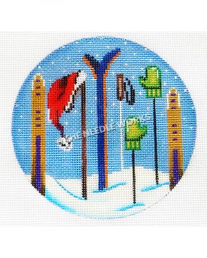 blue ornament with snow skis and poles stuck in snow with green gloves and red Santa hat hanging on tops
