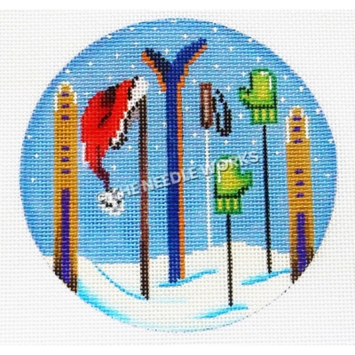 blue ornament with snow skis and poles stuck in snow with green gloves and red Santa hat hanging on tops