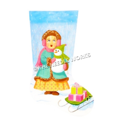 stocking of girl holding snowman standing in snow next to green sled with presents