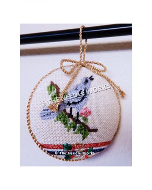 white ornament in gold trim with blue bird on branch with pink flower