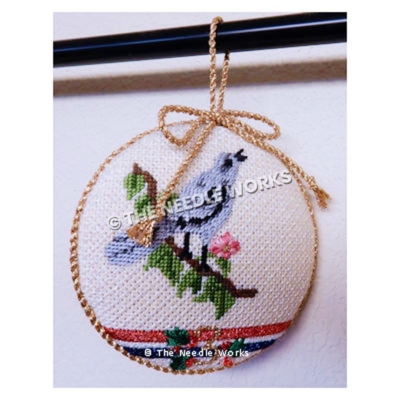 white ornament in gold trim with blue bird on branch with pink flower