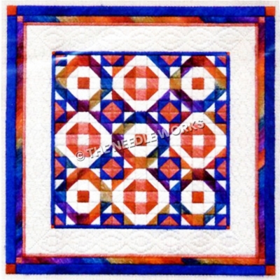 rainbow colored patchwork quilt on white with blue and pink border