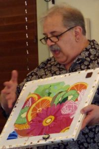 instructor Tony Minieri holding a canvas with colorful flower pattern
