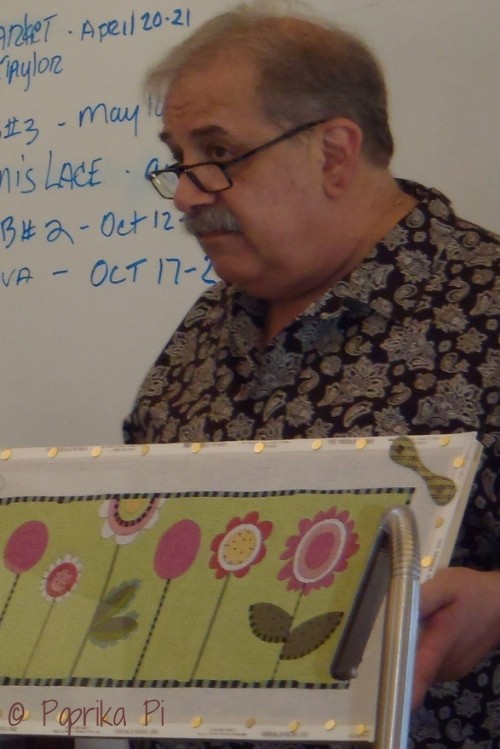 instructor Tony Minieri holding canvas with pink flowers in front of white board