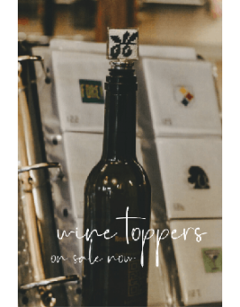 wine toppers on sale now ad with photo of wine bottle with needlepoint topper