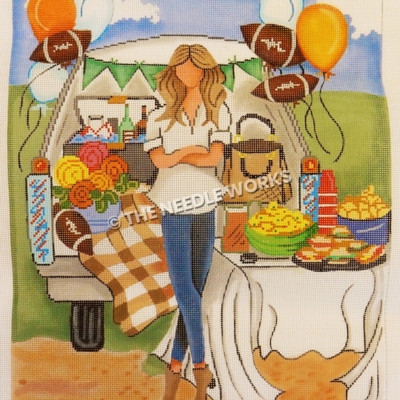 woman standing in front of tailgate filled with food, flowers, purse, and balloons in football shapes, orange and white