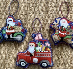 three ornaments with Santa on a motorcycle, fire truck, and reindeer with bags full of gifts