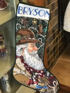 finished stocking profile of Santa in cowboy hat in front of Christmas tree and name Bryson at white top section